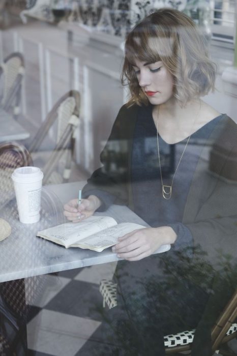 Mujer escribiendo en un caf&eacute; 